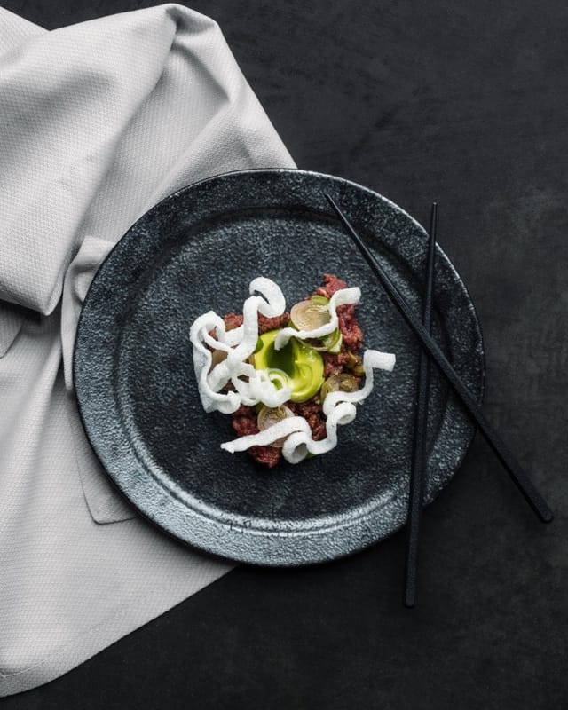 Elegant dish on dark plate at IMA Rooftop Terrace, ideal for corporate gala or upscale wedding.