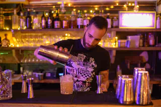 Bartender mixing cocktails in vibrant Hanging Garden Room, perfect for networking events.