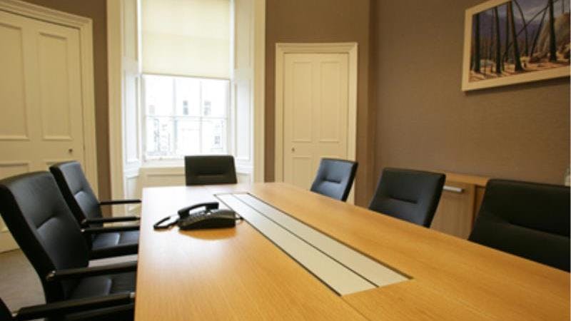 Modern conference room with wooden table and tech, ideal for business meetings.