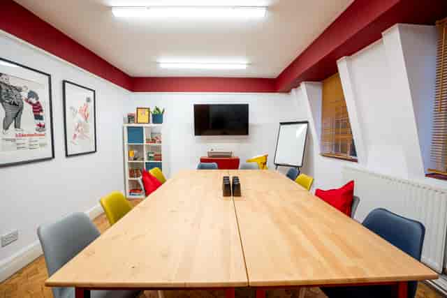 Bright meeting room with wooden table, colorful chairs for collaborative sessions.