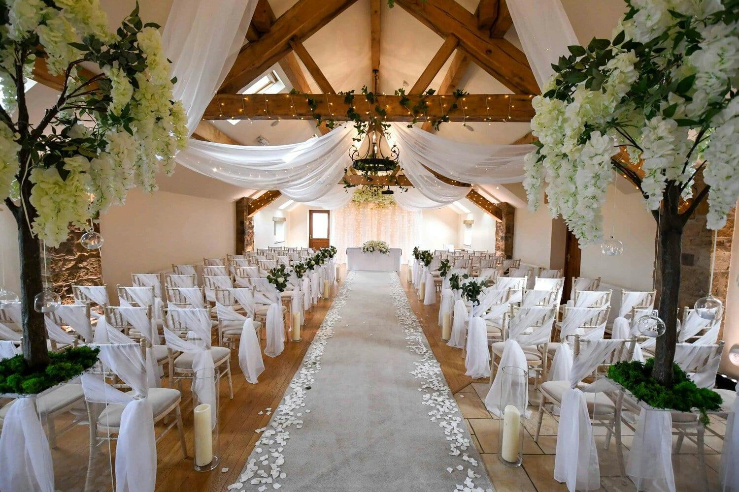 Elegant wedding ceremony setup at Beeston Manor with floral accents and candlelit aisle.