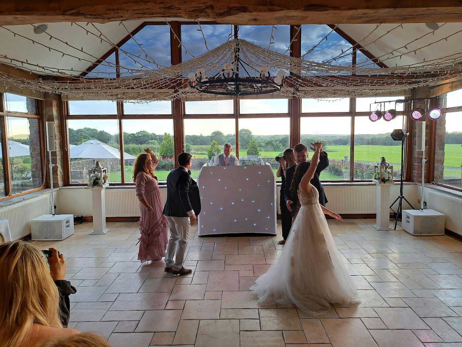 Woodlands Suite at Beeston Manor, vibrant wedding reception with large windows and DJ booth. - Banner