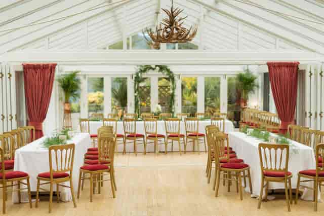 Elegant event space at Woodside Lodge with long tables and red accents. Perfect for gatherings.