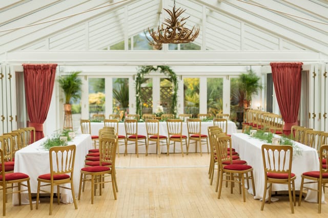 Elegant event space at Woodside Lodge with long tables and red accents. Perfect for gatherings.
