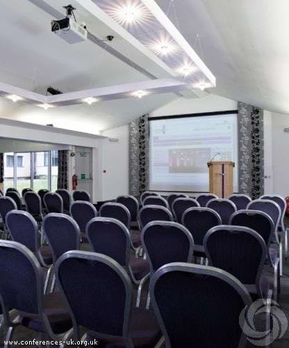 IT Training Suite at Carnegie Conference Centre with chairs, podium, and large screen for events.