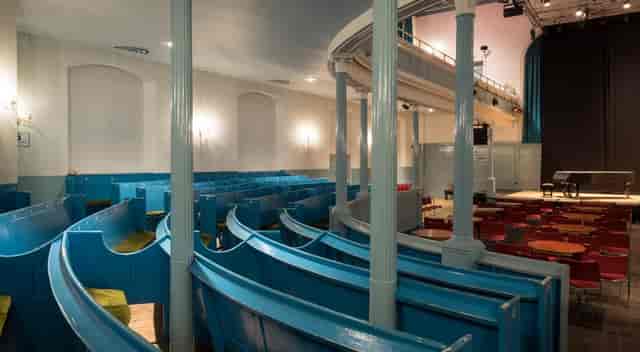 Box Office at The Queen's Hall with tiered seating for events and vibrant blue benches.