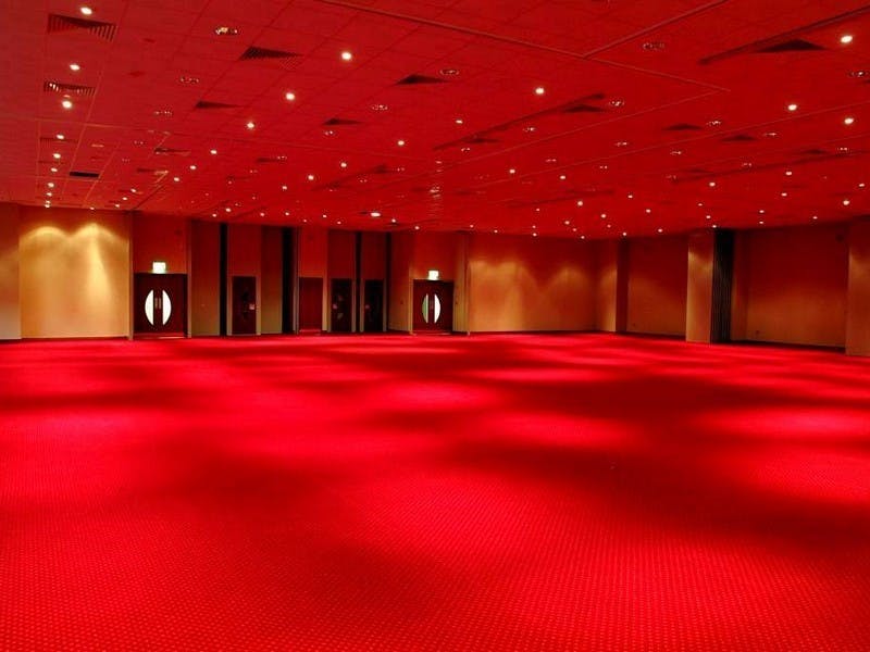 Spacious Harrogate Convention Centre meeting room with red carpet, ideal for conferences and events.