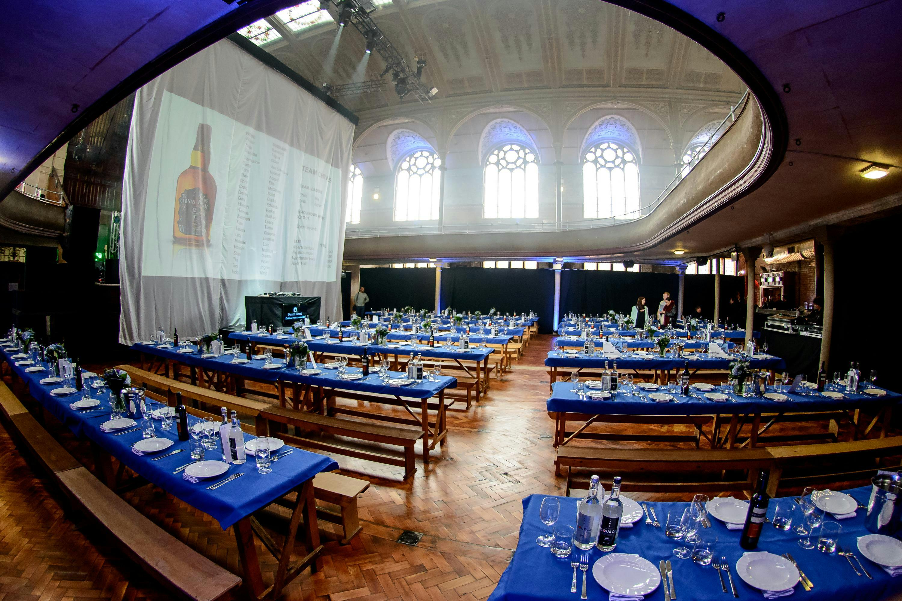 VIP Bar in Albert Hall Manchester, banquet setup with blue tablecloths and presentation screen.