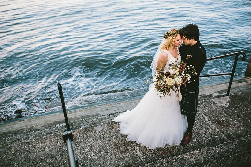 Couple embracing by water at Orocco Pier, perfect for romantic outdoor weddings.