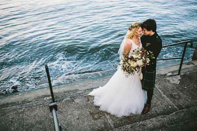 Couple embracing by water at Orocco Pier, perfect for romantic outdoor weddings.