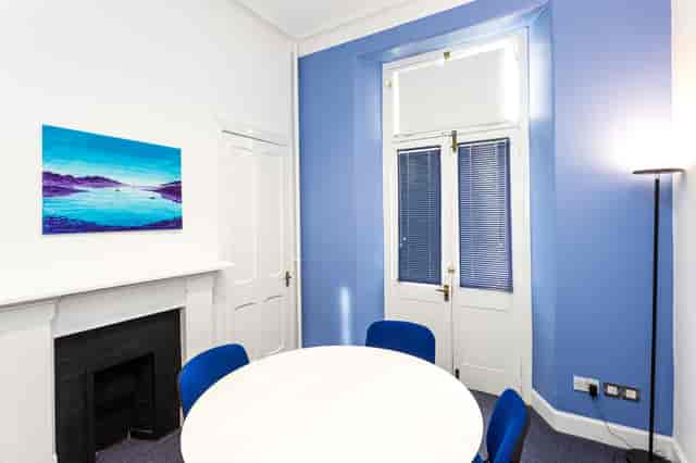Bright boardroom with round table and blue chairs, ideal for meetings and collaborations.