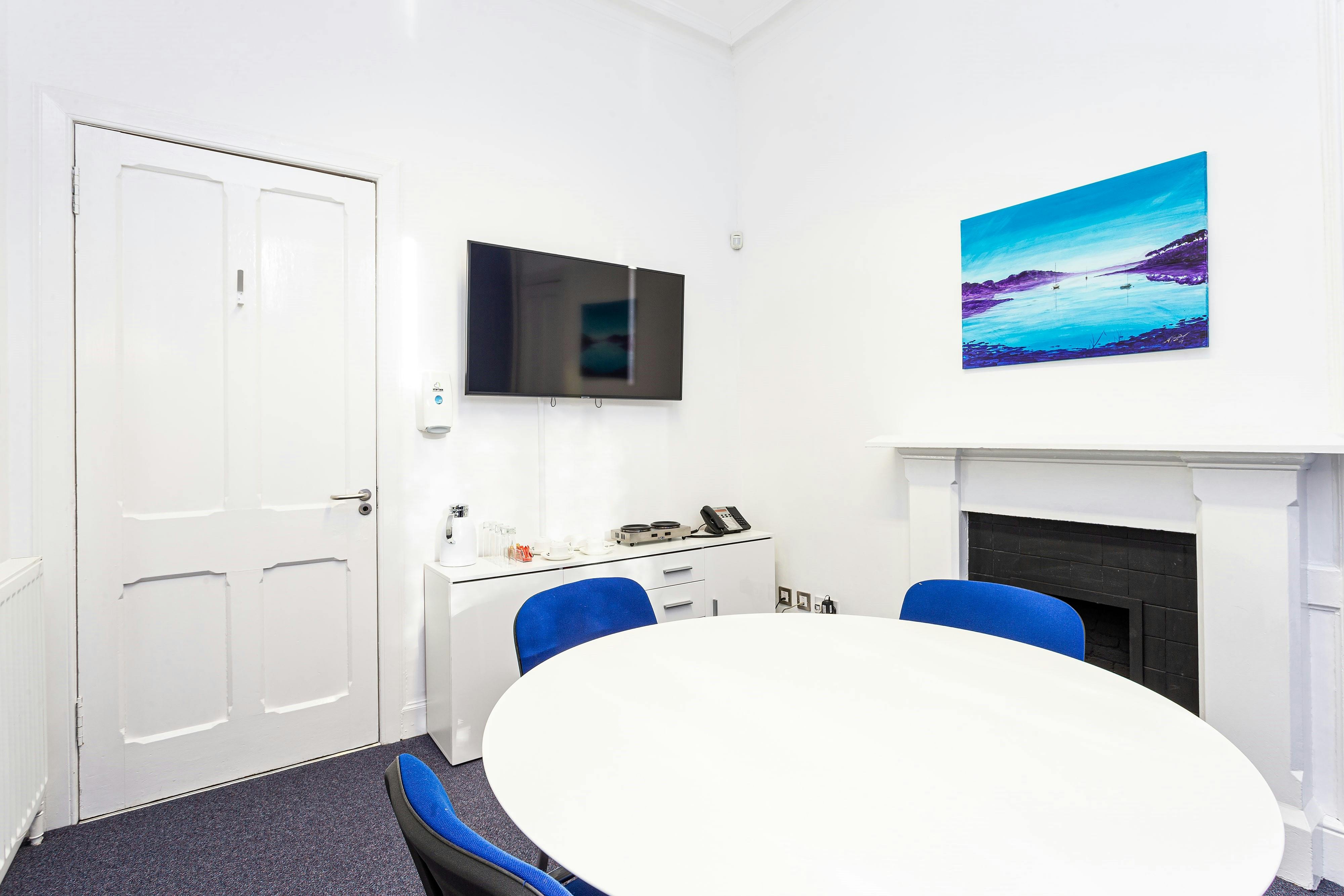 Modern boardroom with round table and blue chairs, perfect for meetings and brainstorming.