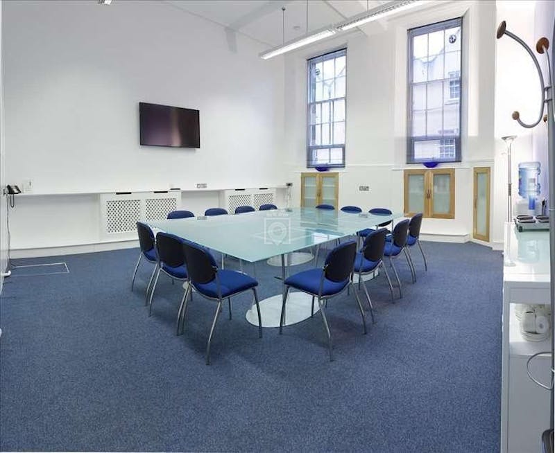 Modern meeting room with glass table and blue chairs, perfect for presentations and collaboration.