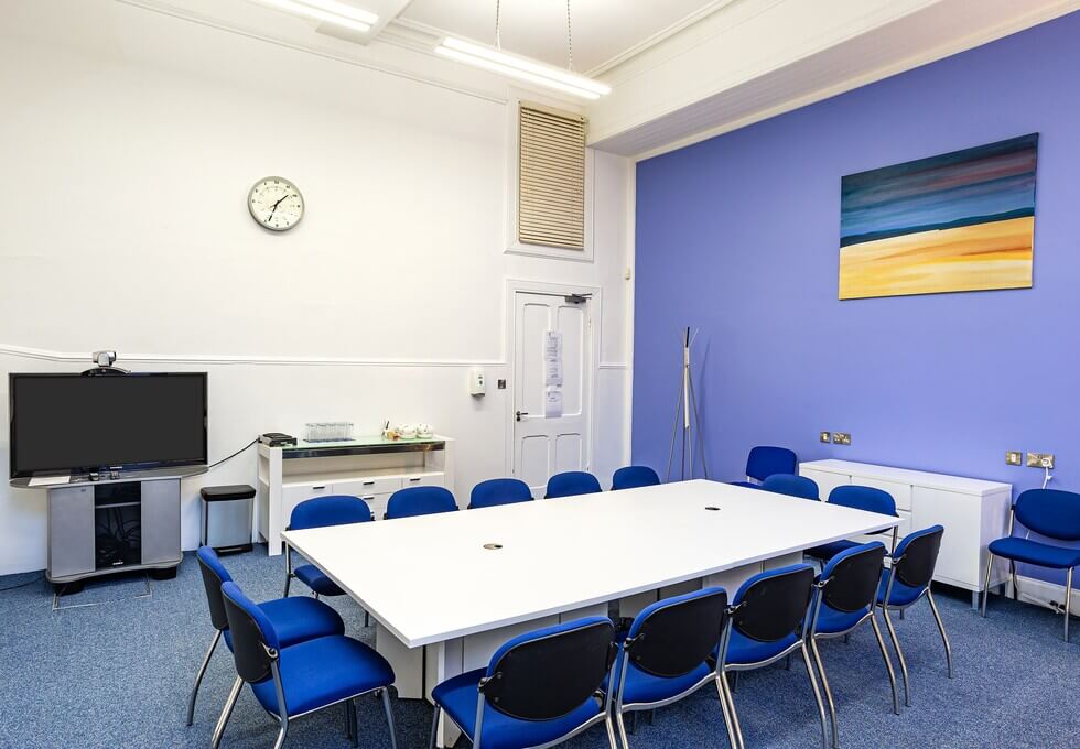 Well-lit meeting room with large white table and blue chairs for productive discussions.