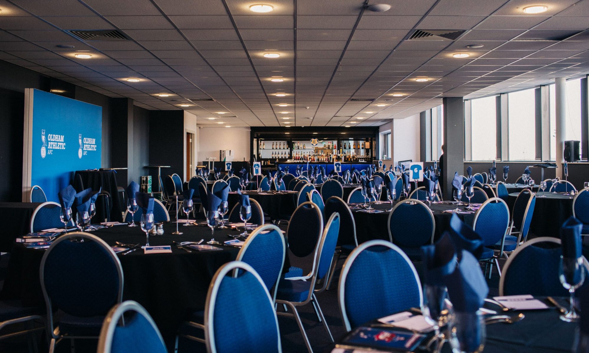 Event space in Oldham with round tables, blue napkins for corporate meetings or galas. - Banner