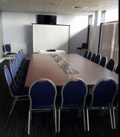 Meeting room in Oldham Event Centre with large table and blue chairs for workshops.