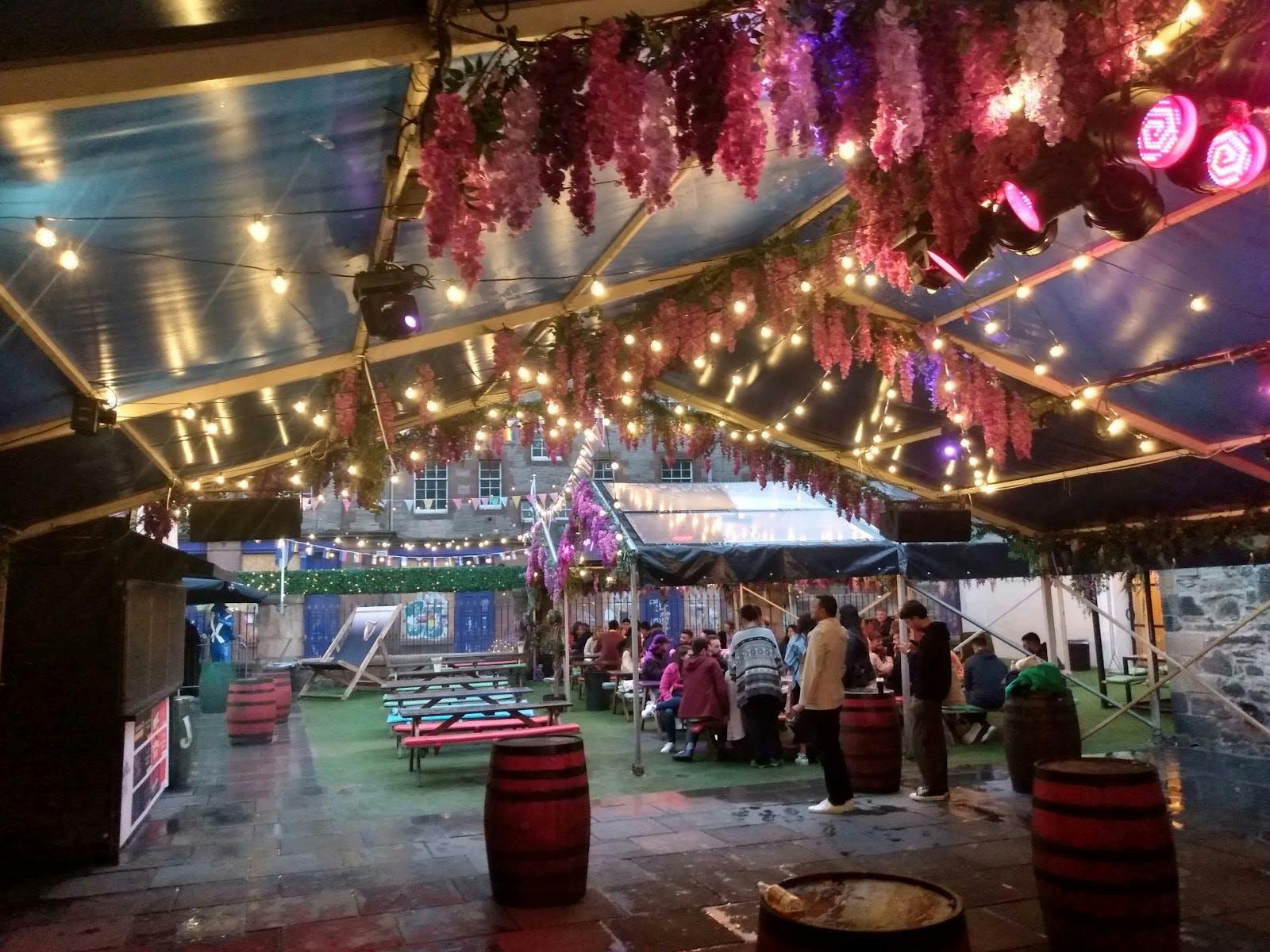 Karaoke Pods in vibrant outdoor event space with string lights and flowers for celebrations.