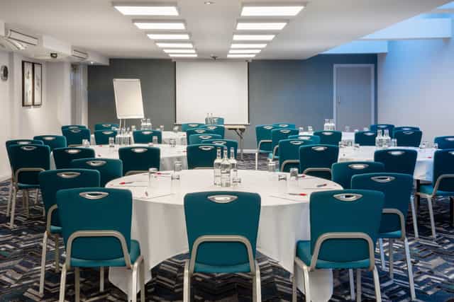 Meeting room with circular tables at Leonardo Hotel London Heathrow for conferences.