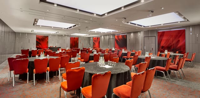 Event space at City Suites, Park Plaza London: round tables, black linens, red chairs.