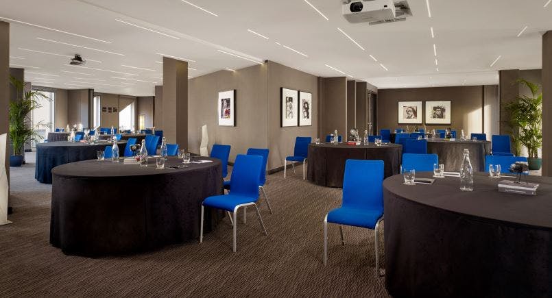 Modern meeting space with round tables and blue chairs, perfect for corporate workshops.