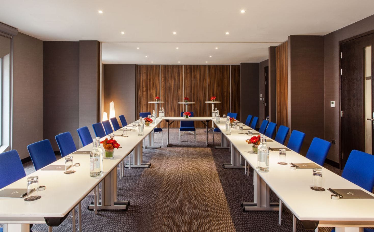 Modern meeting room with U-shaped tables, ideal for professional gatherings and presentations.