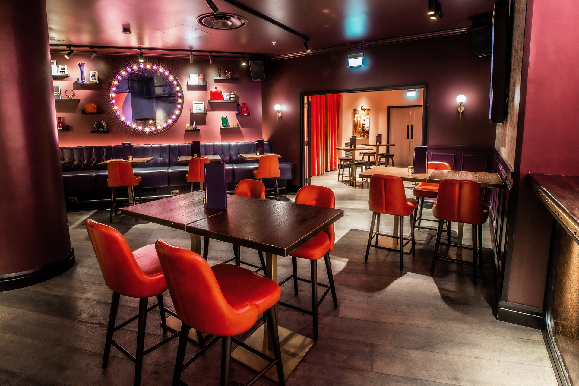 Stylish event space at Puttshack Bank with vibrant orange chairs for gatherings. - Banner