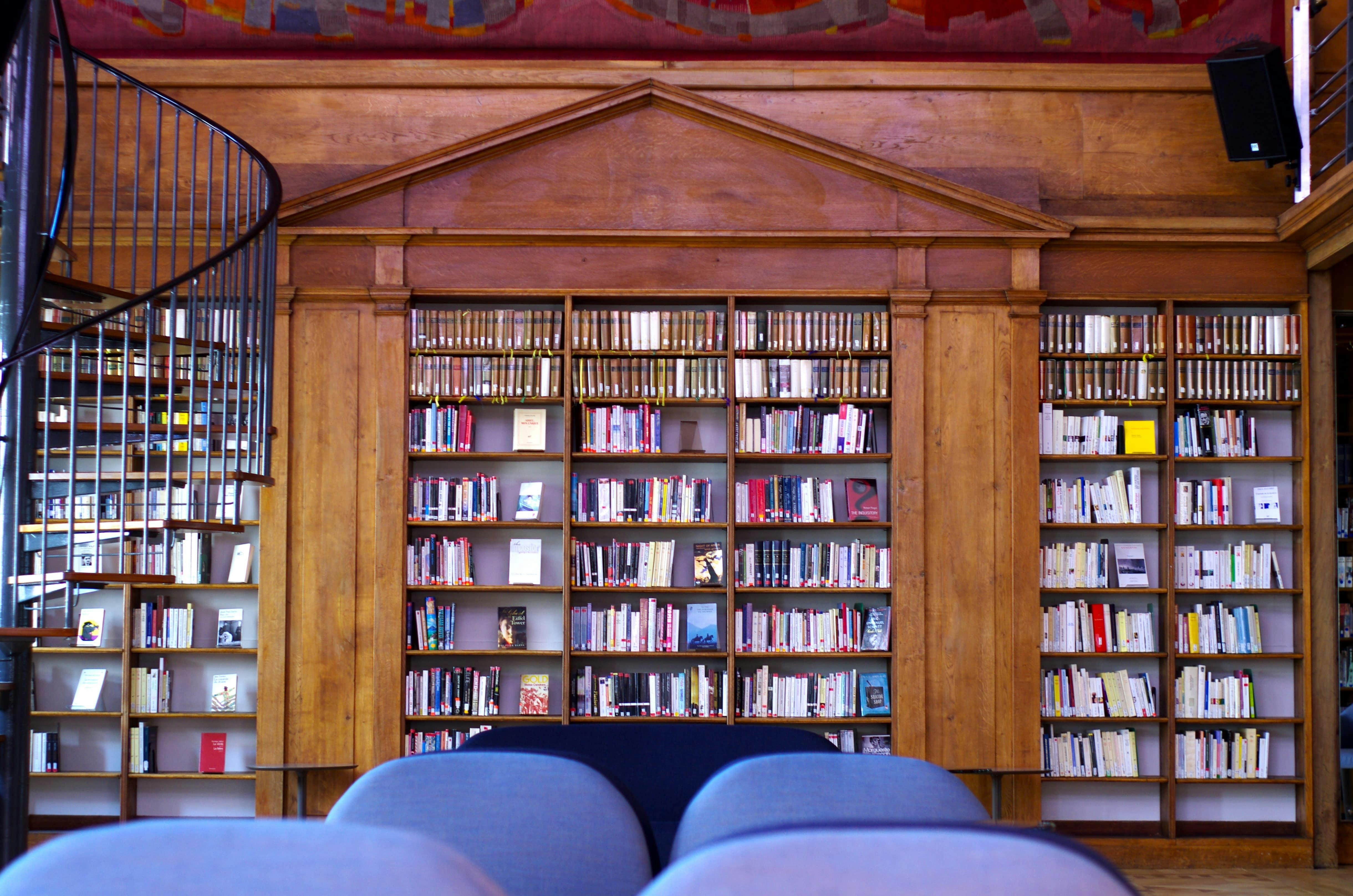 Art Deco library with wooden shelves and spiral staircase, ideal for literary events.