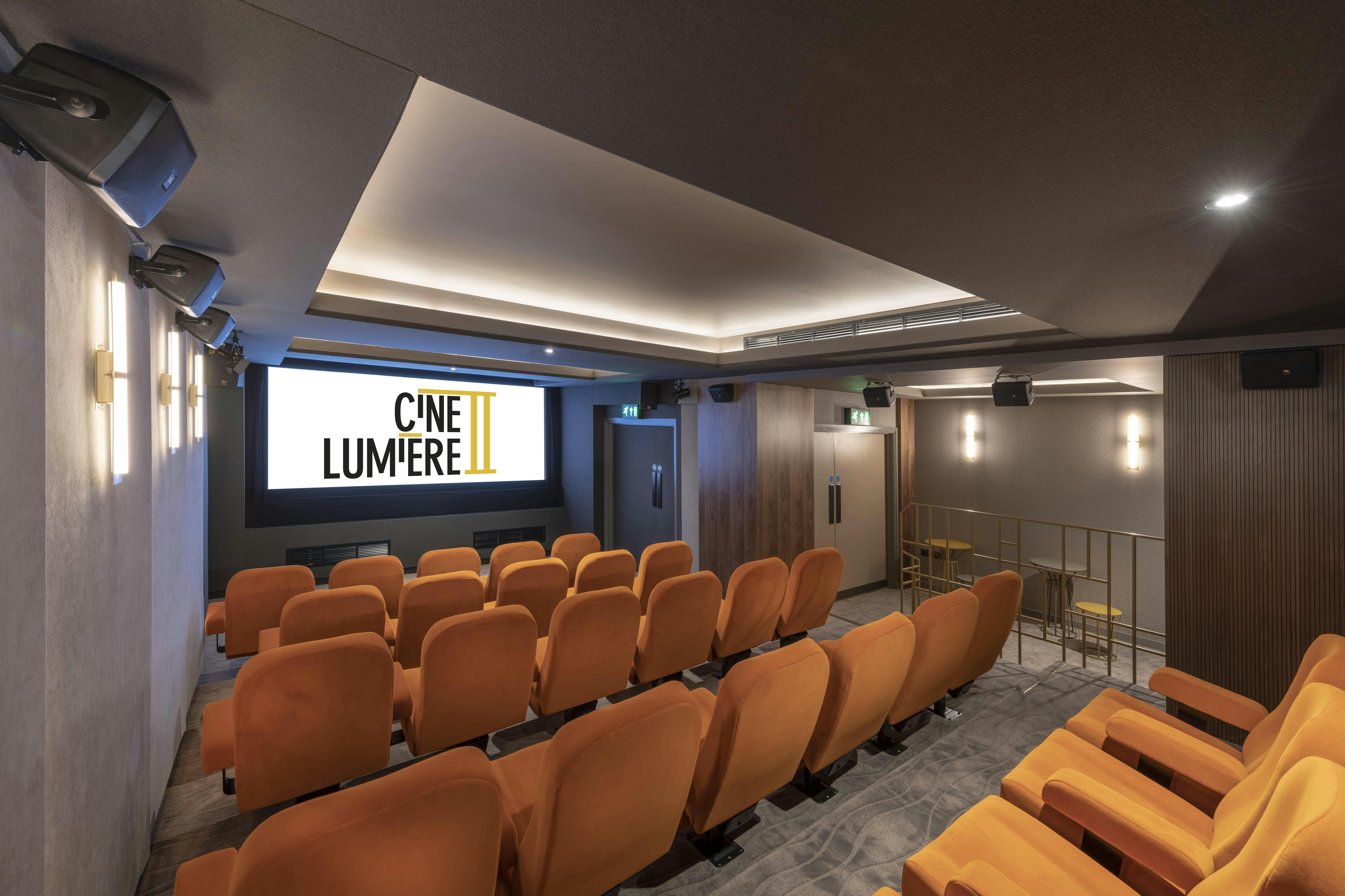 Ciné Lumière 2: modern screening room with plush orange seating for film screenings and events.