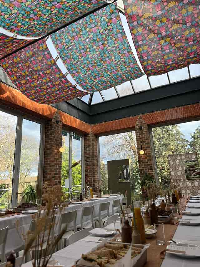 Glasshouse event space with glass ceiling, vibrant decor for gatherings and celebrations.