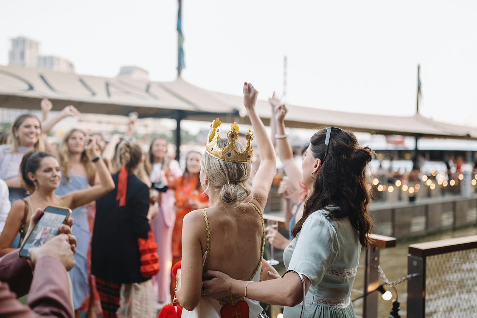 Lively bachelorette party at Woods Quay with guests cheering by the waterfront.