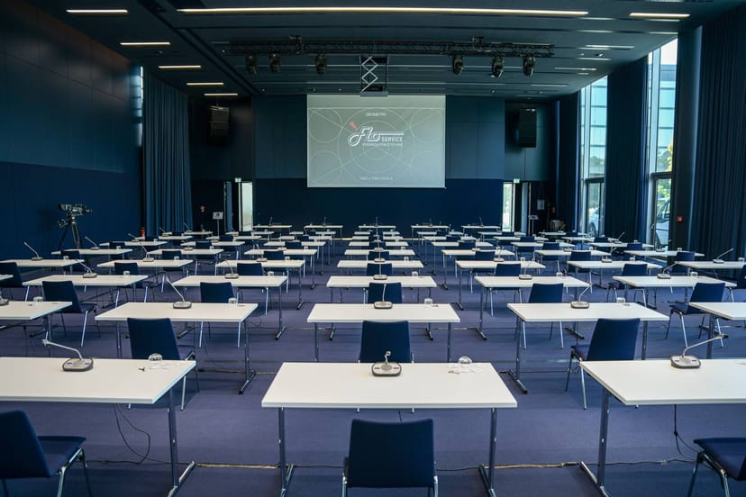 Conference room setup with tables, chairs, and a large screen for events and meetings.