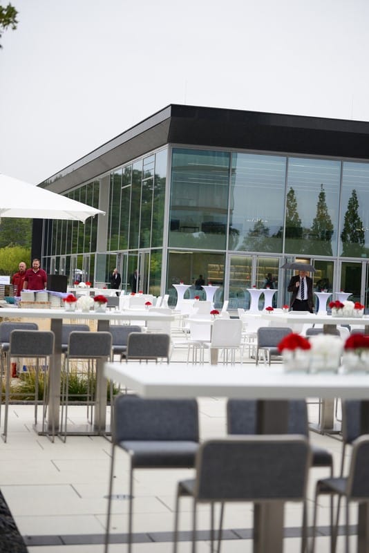 Elegant outdoor event space with modern furniture and red roses for corporate gatherings.