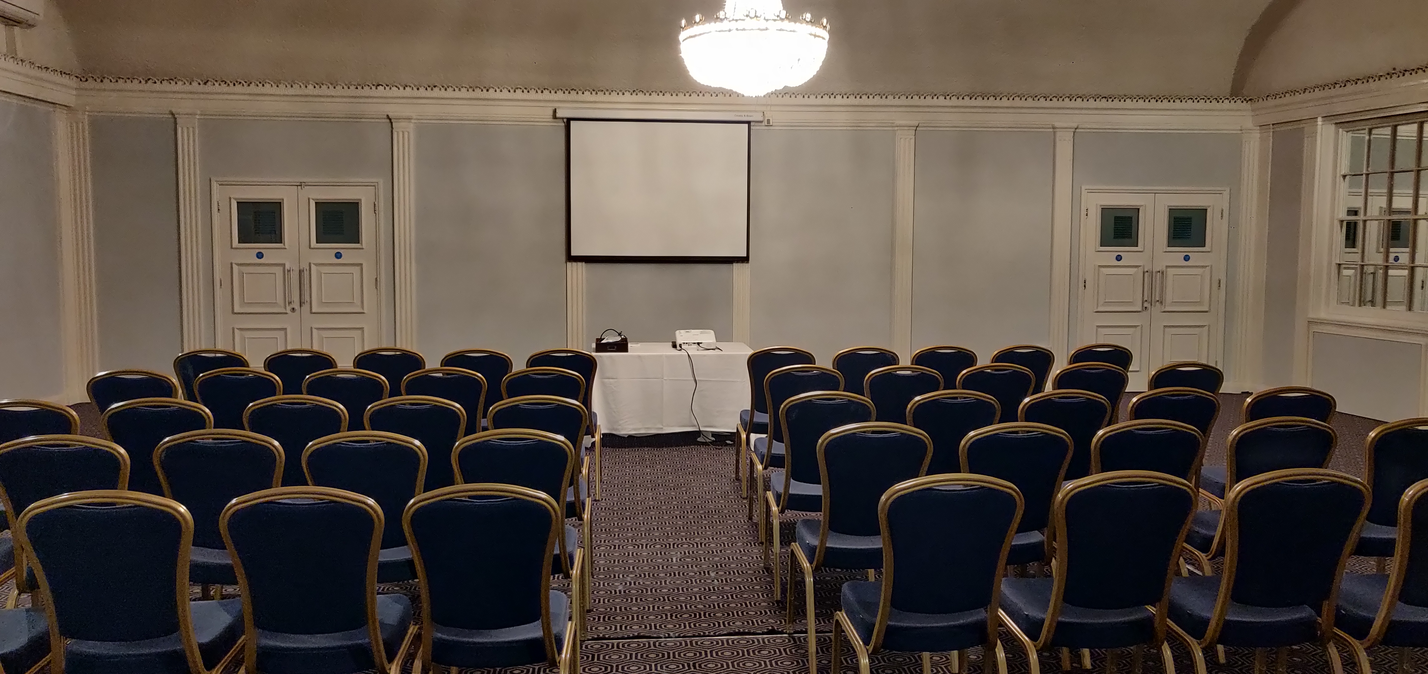 Elegant meeting room at ABode Hotel with blue chairs for presentations. - Banner