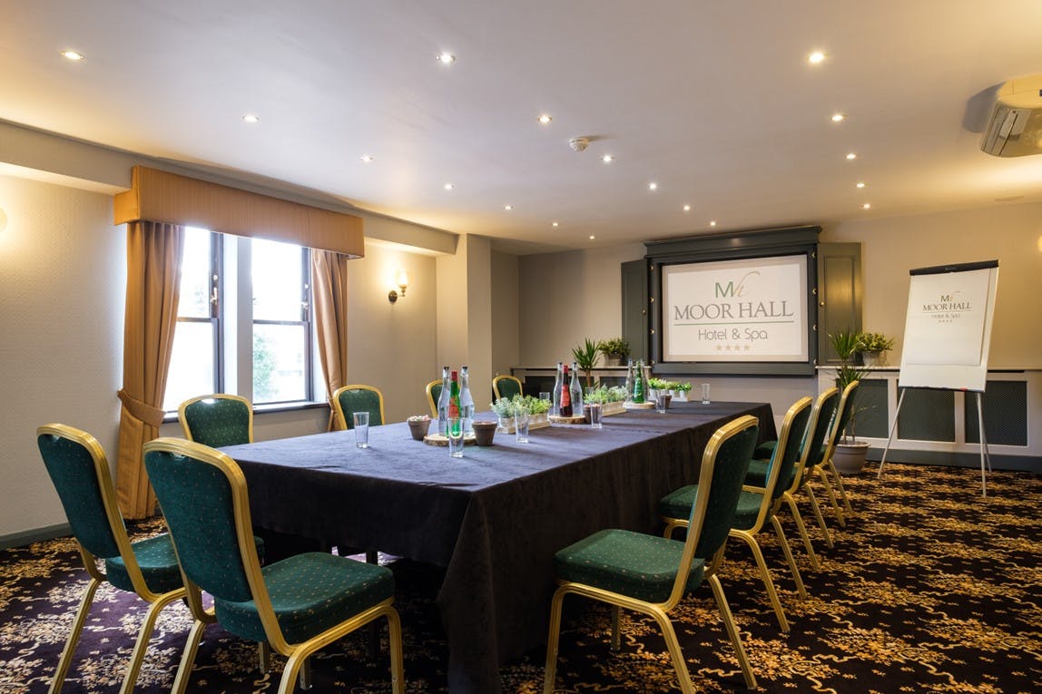 Wentworth Room at Moor Hall Hotel: elegant meeting space with projector and green chairs.