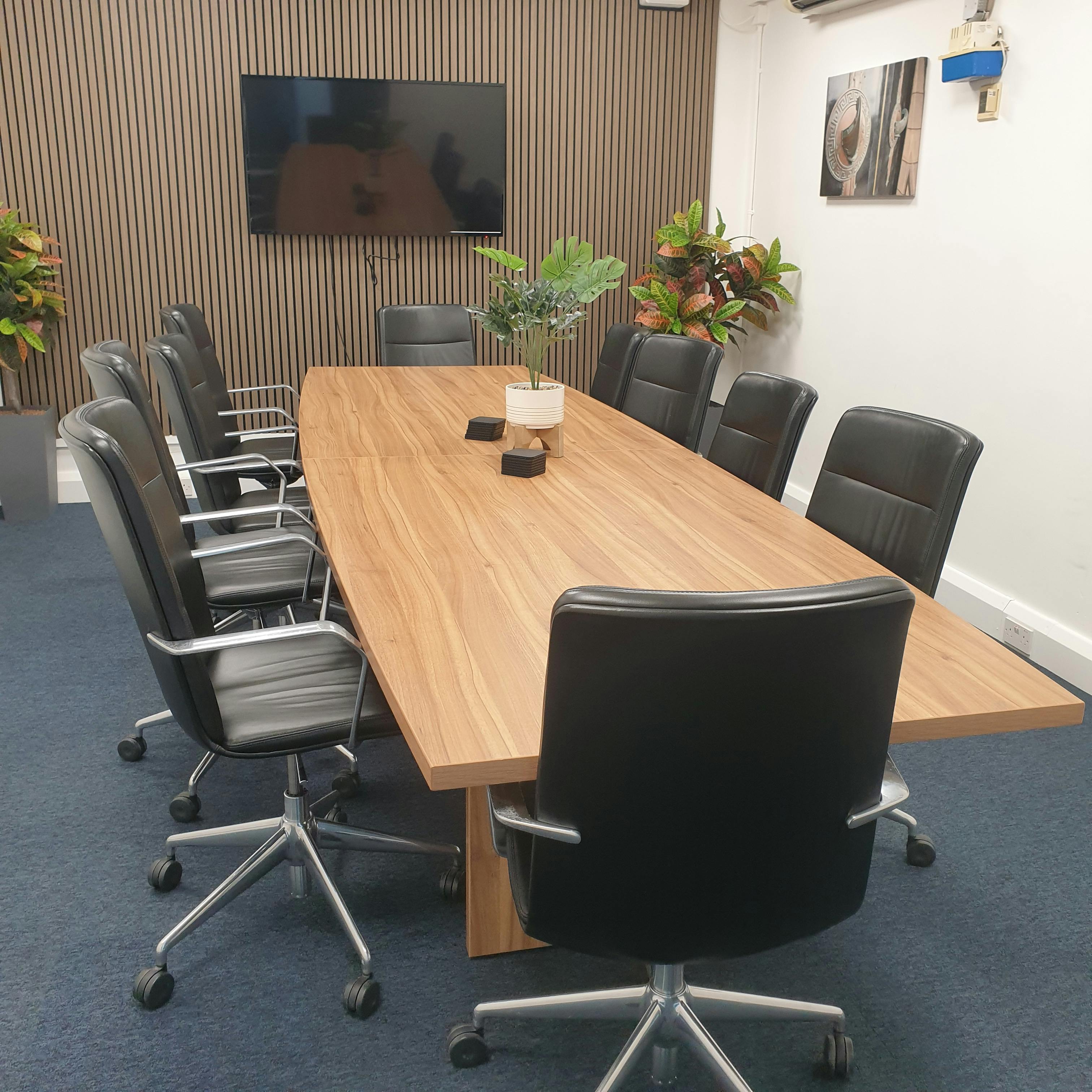 Modern boardroom with wooden table and ergonomic chairs, perfect for meetings.