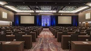 Centennial Ballroom setup for corporate conference with dual screens and ambient lighting.