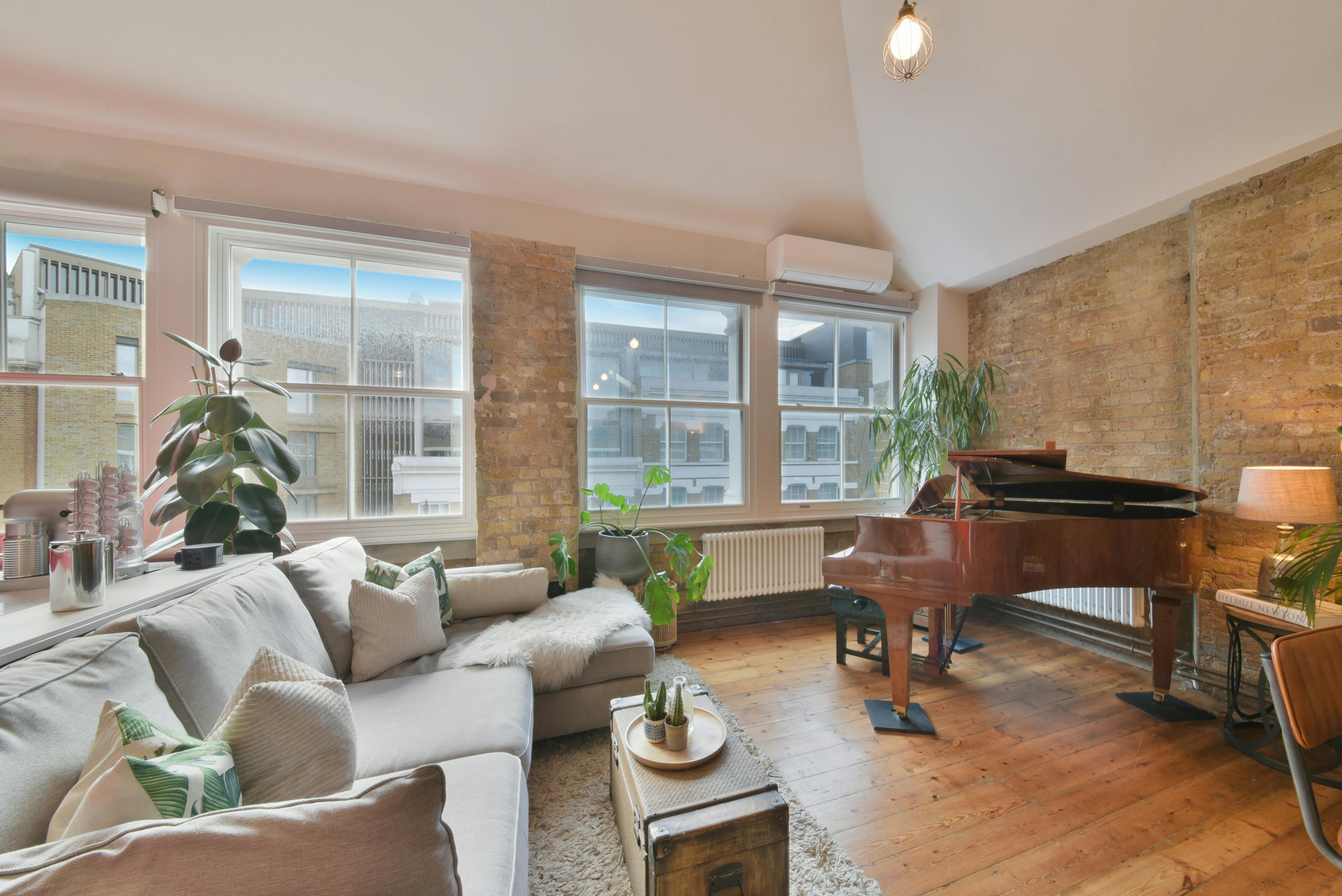 Cozy meeting space in The Treehouse Loft with grand piano, ideal for gatherings and brainstorming.