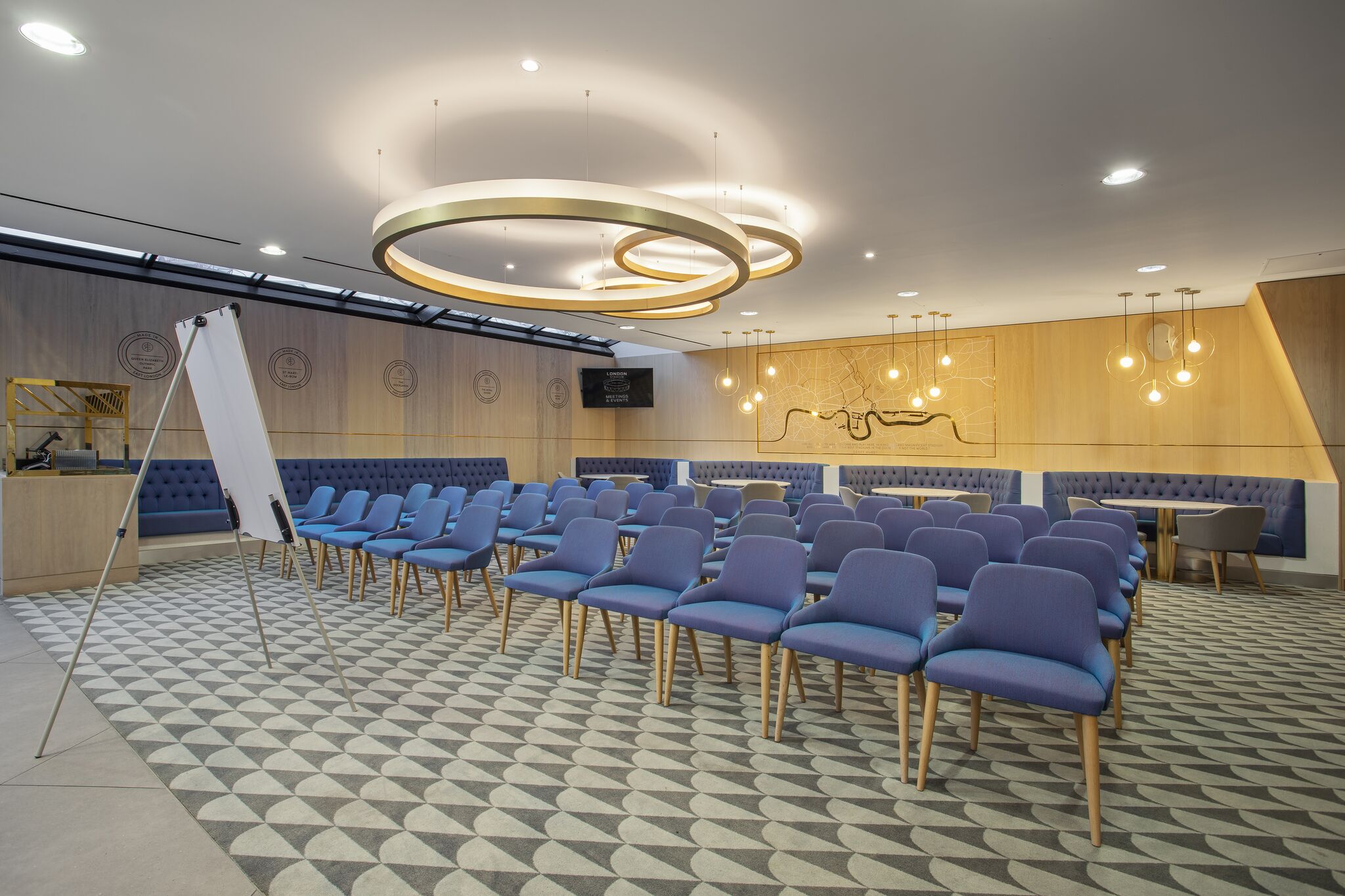Modern meeting space at The Royal East, featuring blue chairs and stylish lighting for workshops. - Banner