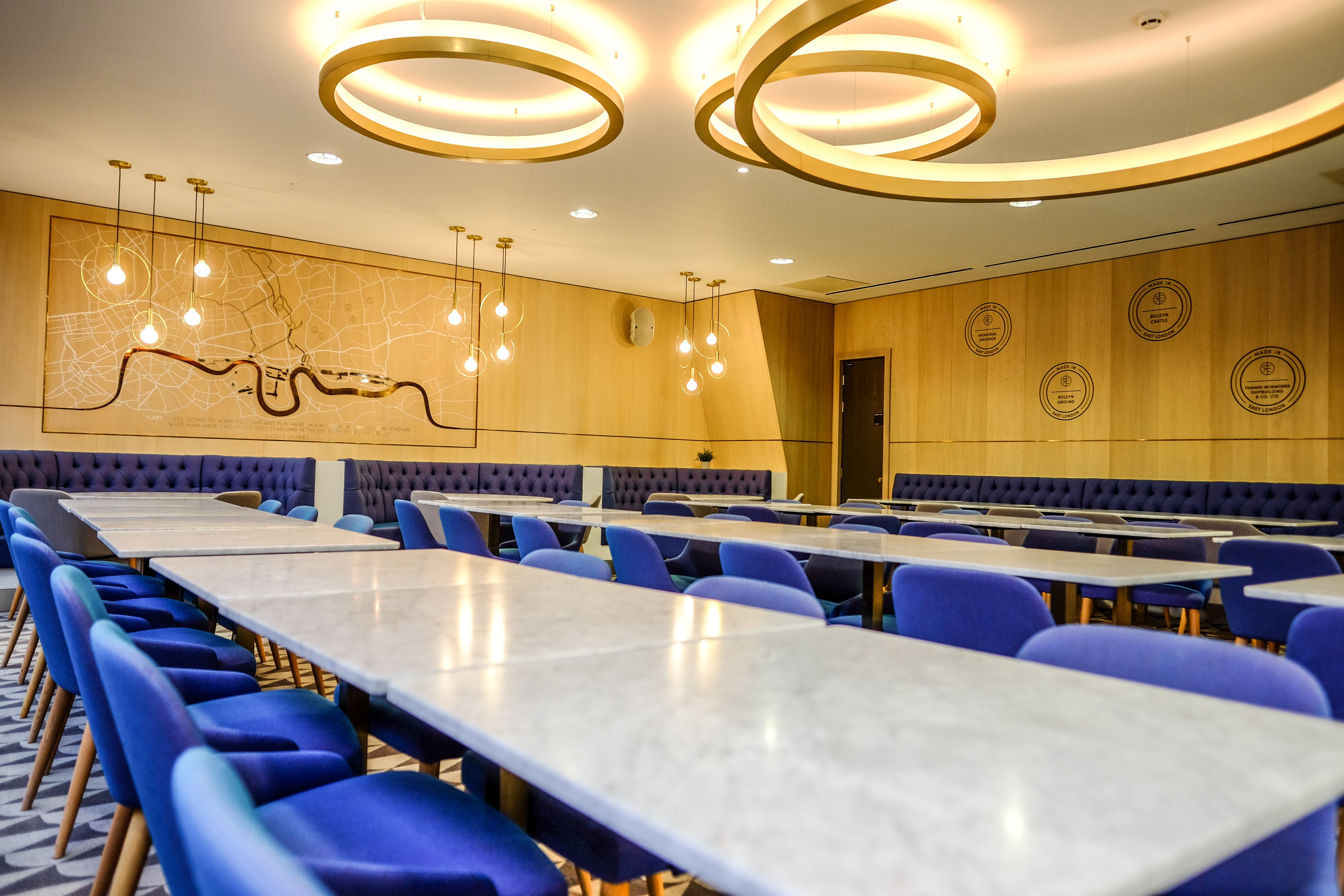Modern meeting space at The Royal East, featuring marble tables and plush blue chairs. - Banner