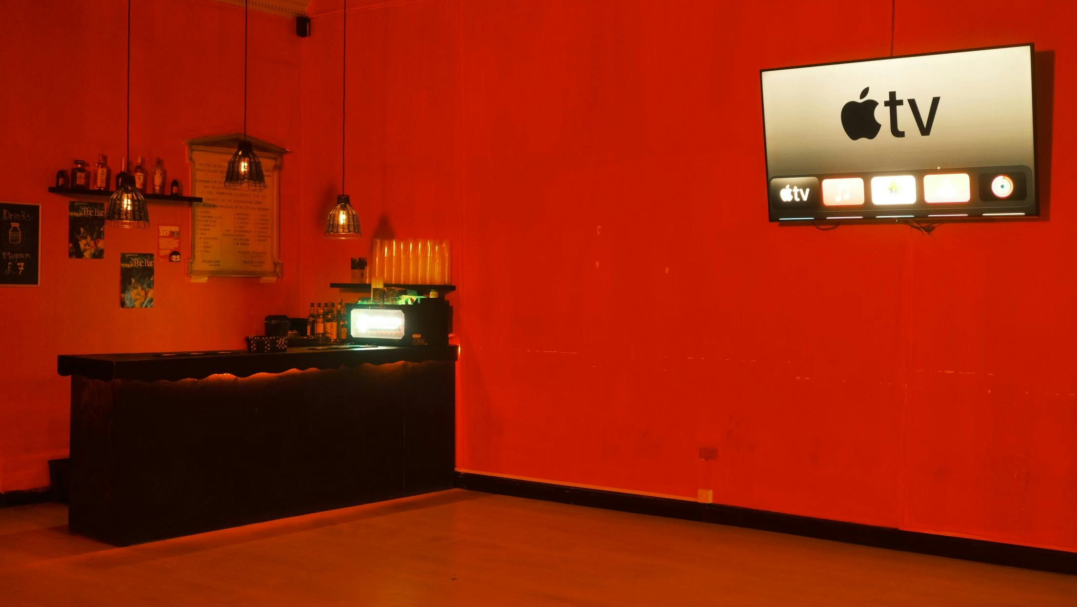 Vibrant Orange Room event space with sleek bar, ideal for gatherings and presentations.