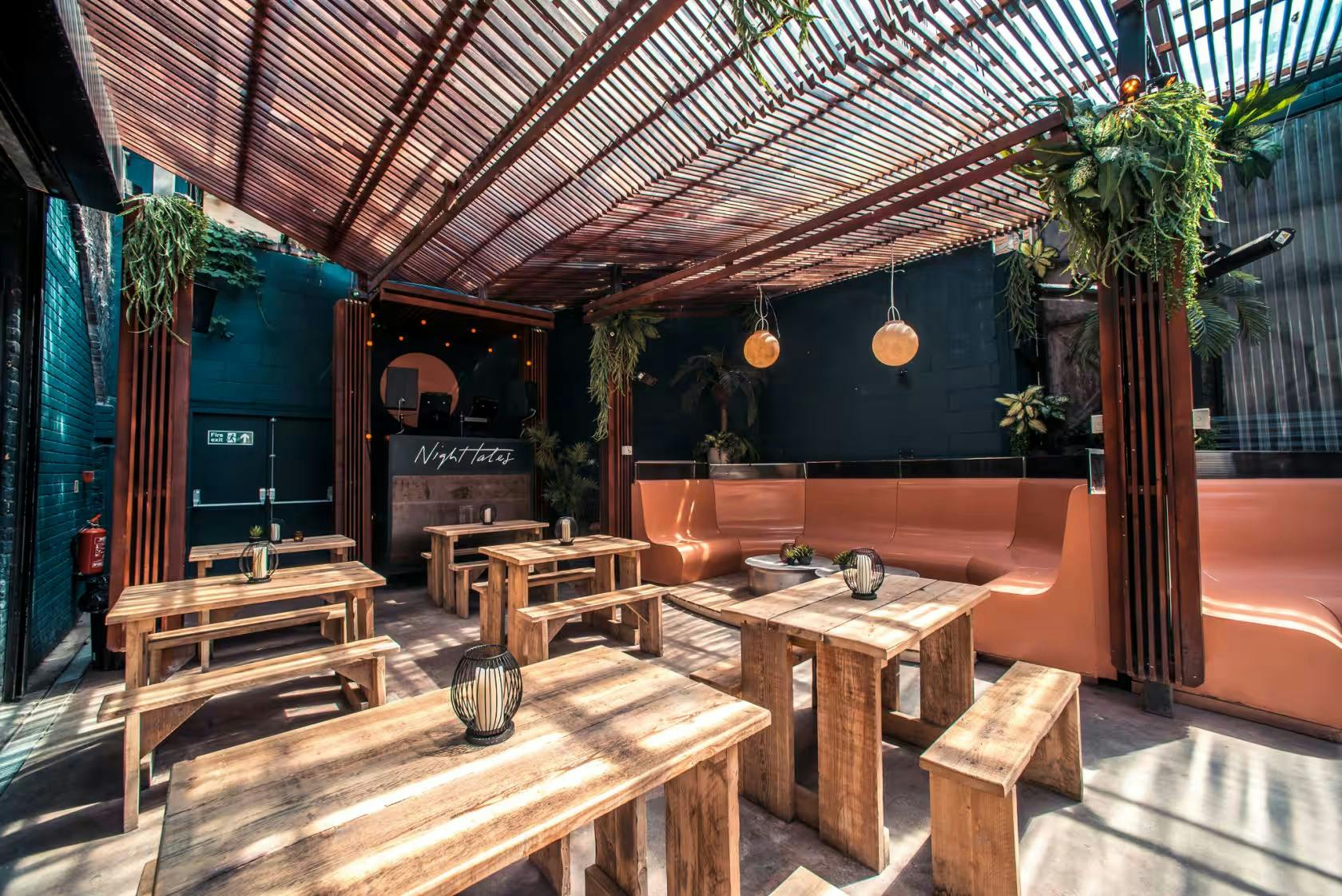 Stylish outdoor venue with wooden tables and greenery for casual events and networking.