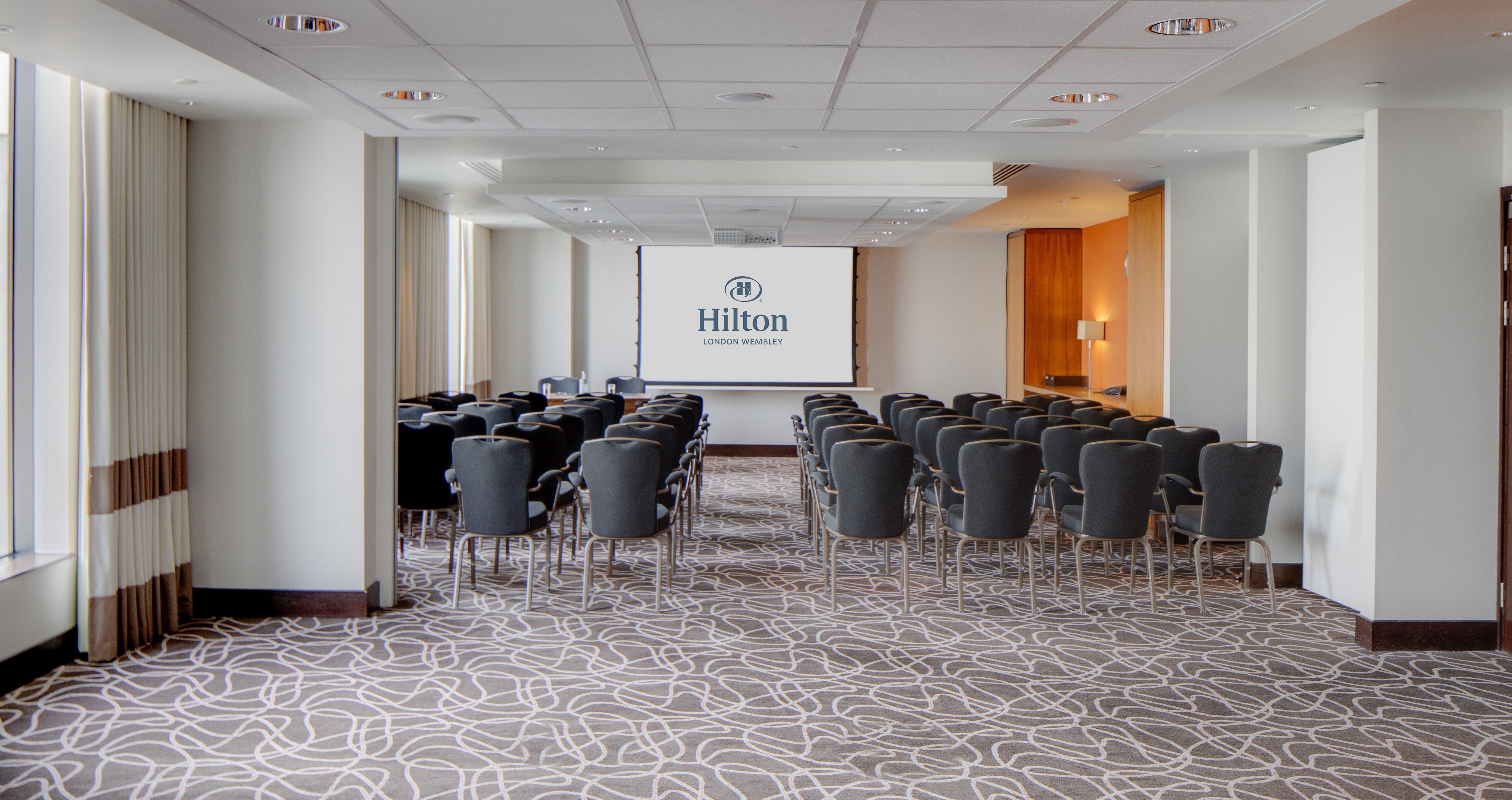 Spacious Hilton London Wembley meeting room with modern design for corporate events. - Banner