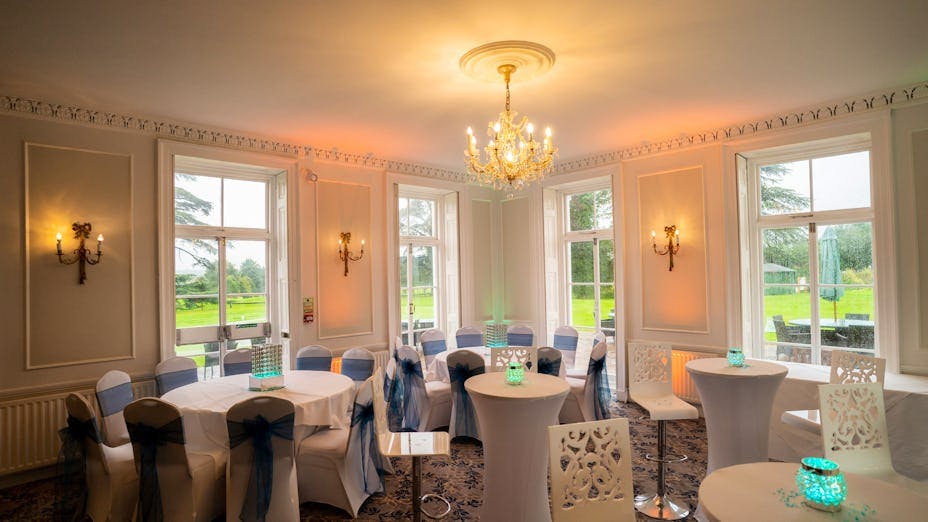 Elegant event space at Dyrham Park Country Club with round tables and vibrant centerpieces.