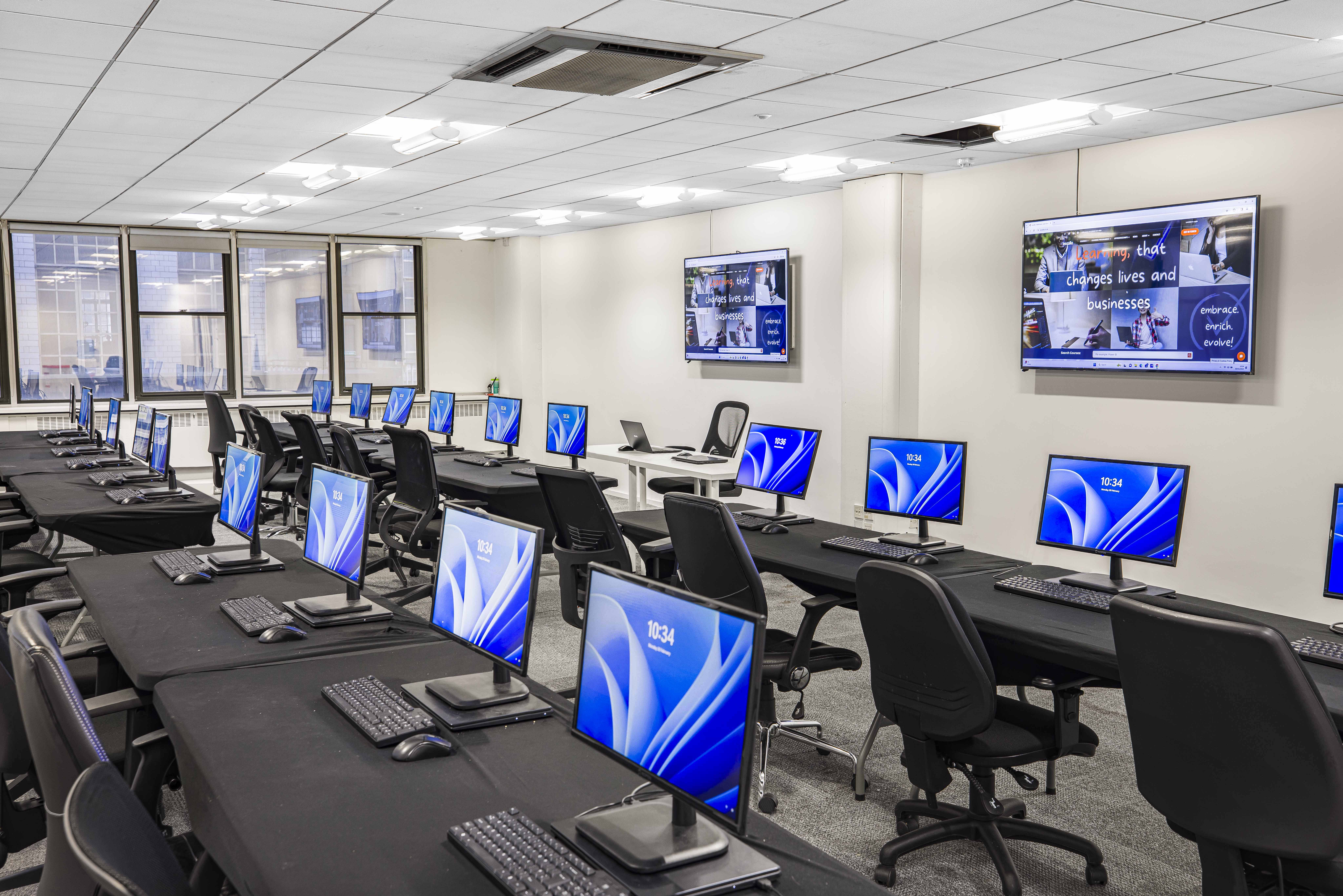 Modern IT training room with workstations, ideal for hybrid meetings and training sessions. - Banner