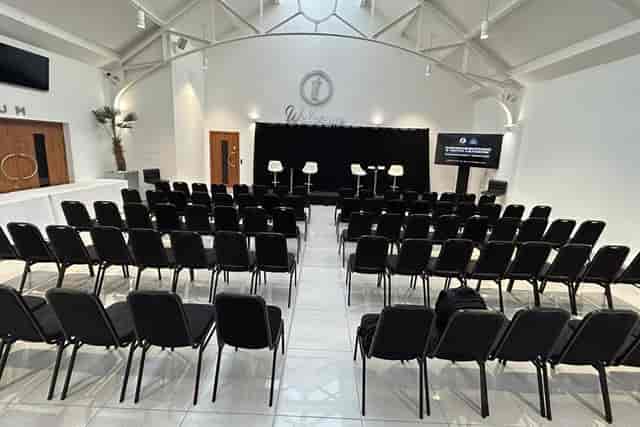 Modern event space in The Atrium, featuring black chairs and a sleek stage for conferences.