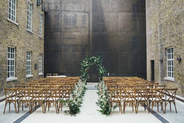 Elegant wedding venue with floral arch and wooden chairs in Hackney Venues.