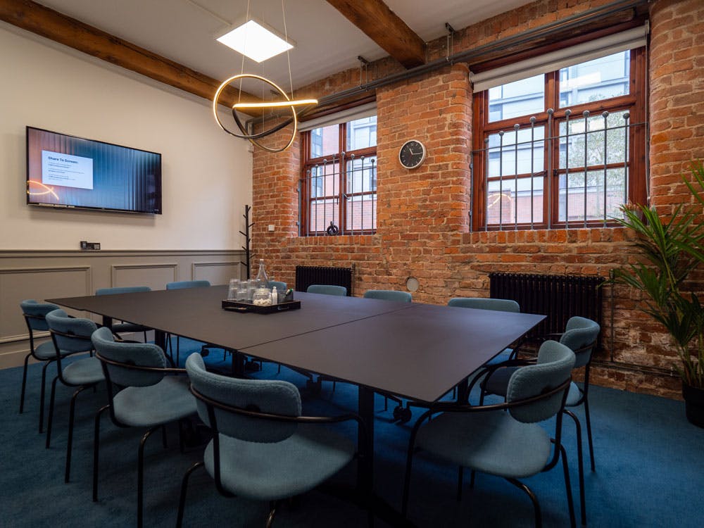 Modern conference room with black table, blue chairs, ideal for meetings and events.