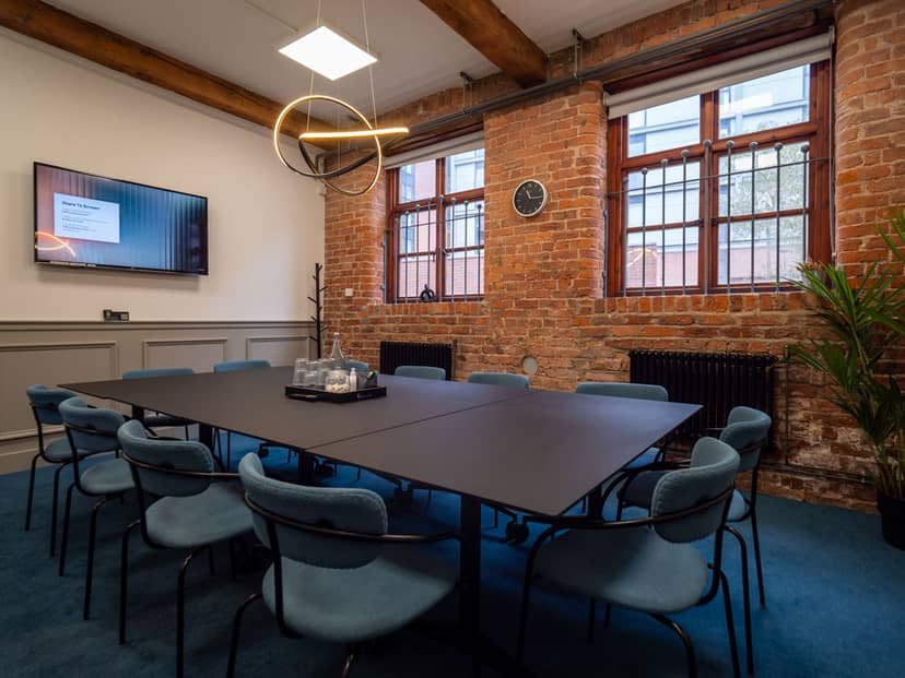 Modern conference room with black table, blue chairs, ideal for meetings and events.