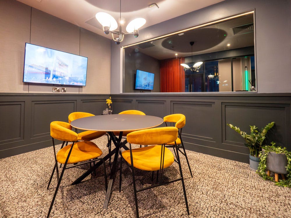 Modern meeting room with round table and yellow chairs, perfect for team brainstorming sessions.