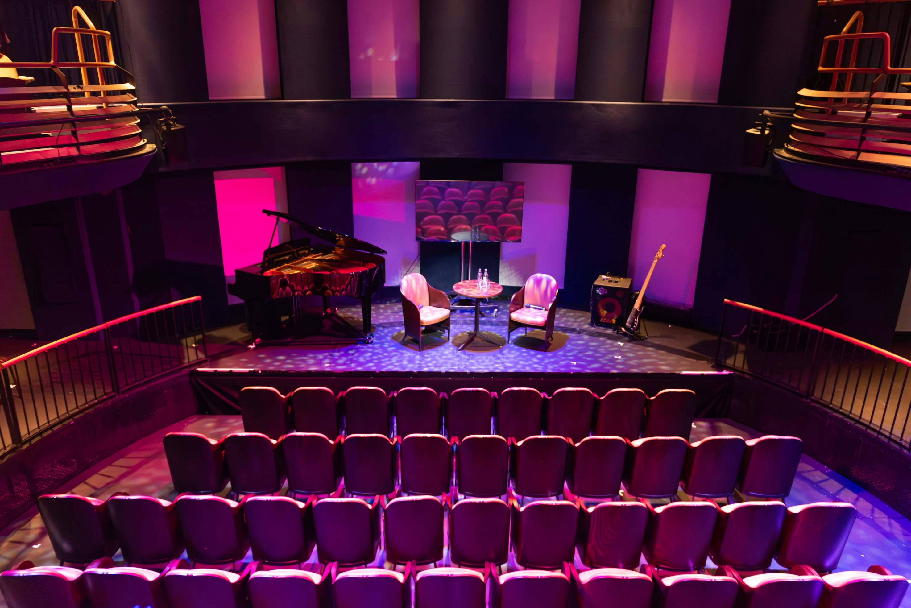 Intimate event space with tiered seating, grand piano for performances and discussions.